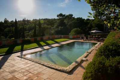 Chambre lumineuse avec lit double, couvre-lit bleu, lampe de chevet et porte-fenêtre donnant sur un jardin.