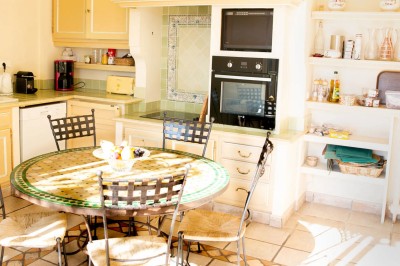 Chambre lumineuse avec lit double, couvre-lit bleu, lampe de chevet et porte-fenêtre donnant sur un jardin.