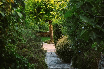 Chambre lumineuse avec lit double, couvre-lit bleu, lampe de chevet et porte-fenêtre donnant sur un jardin.
