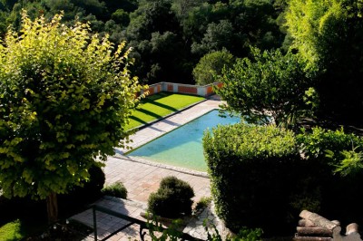 Chambre lumineuse avec lit double, couvre-lit bleu, lampe de chevet et porte-fenêtre donnant sur un jardin.