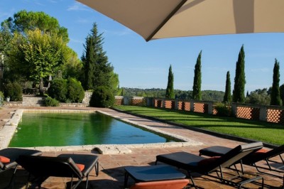 Chambre lumineuse avec lit double, couvre-lit bleu, lampe de chevet et porte-fenêtre donnant sur un jardin.