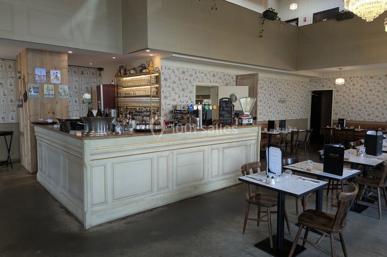 Salle de restaurant lumineuse avec un comptoir en bois clair, tables dressées et décor mural vintage.