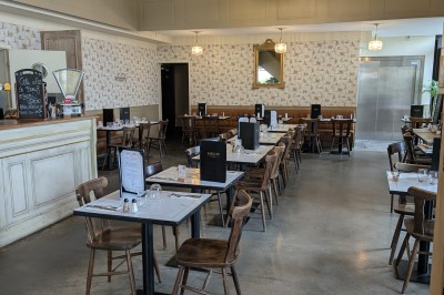 Miniature Rez de Chaussée Poulet rôti garni d'oignons caramélisés sur une assiette, avec une main utilisant une fourchette en arrière-plan.