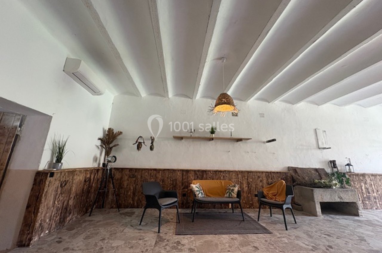 Espace intérieur avec plafond voûté, mobilier minimaliste et décoration naturelle sur un mur en bois et blanc.