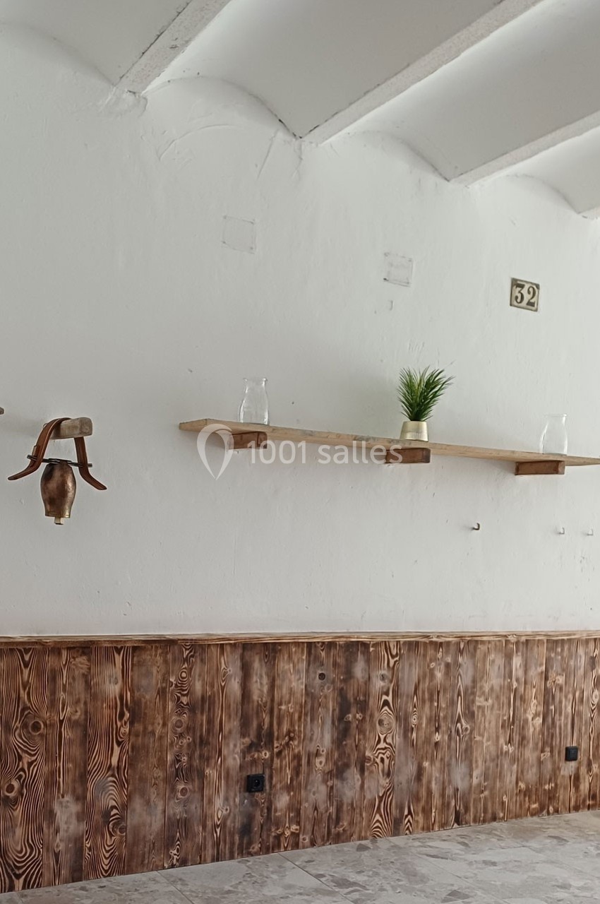 Mur intérieur blanc avec étagères en bois, décorées d'une plante verte et de verres, et lambris en bois en bas.
