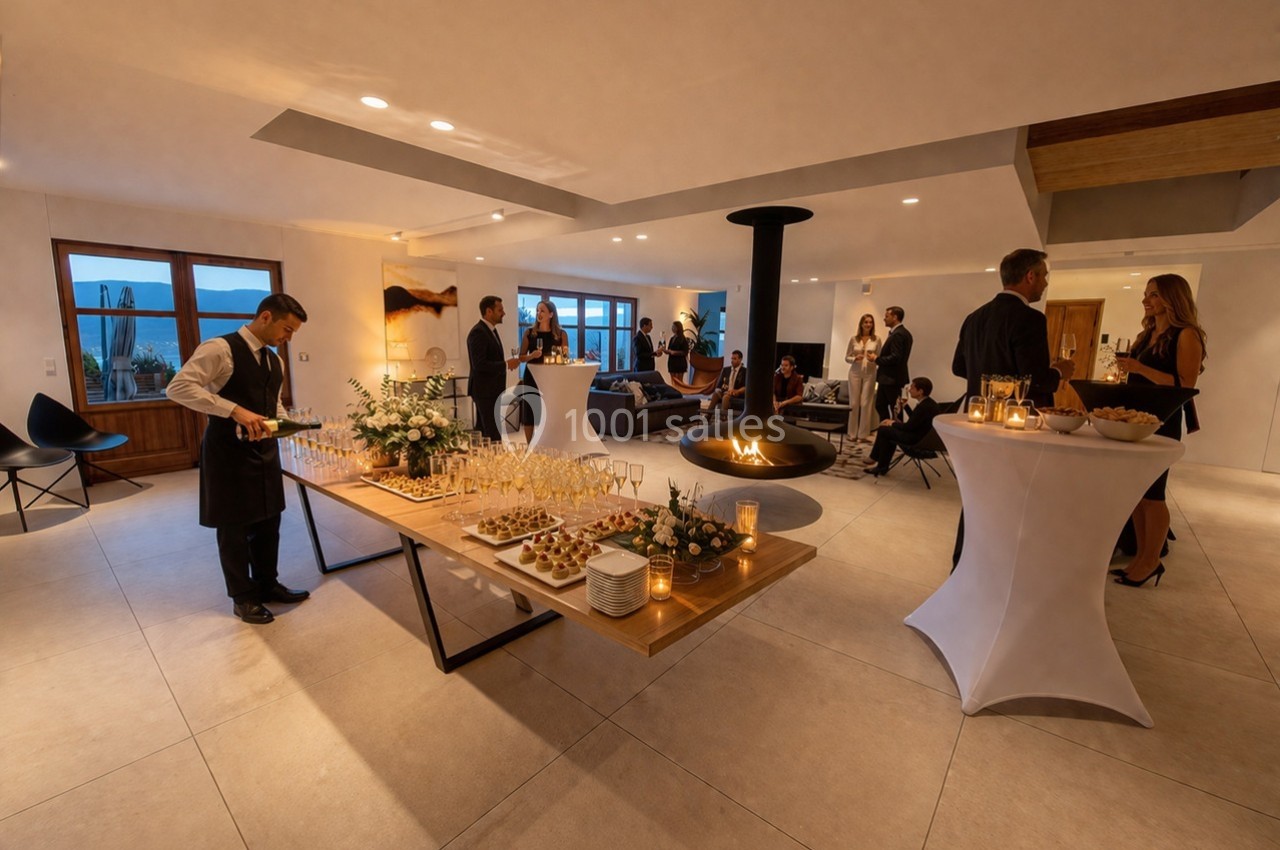 Salle élégante avec invités debout, buffet dressé, serveur en action et cheminée centrale allumée.