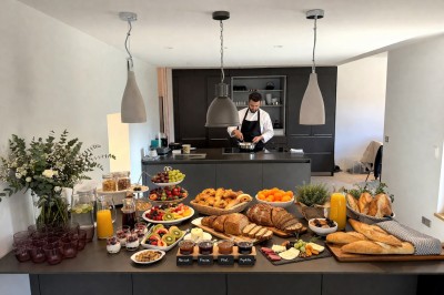 Table extérieure dressée avec des verres à vin, des fleurs, des bougies et des plateaux de nourriture.