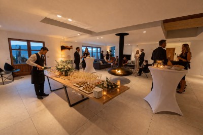 Table extérieure dressée avec des verres à vin, des fleurs, des bougies et des plateaux de nourriture.