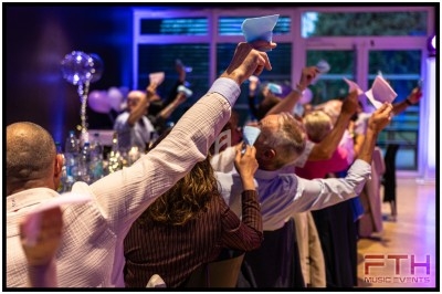 Quatre personnes regardent un écran lumineux dans un photomaton rétro, dans une pièce aux murs en pierre.