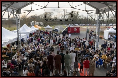 Quatre personnes regardent un écran lumineux dans un photomaton rétro, dans une pièce aux murs en pierre.