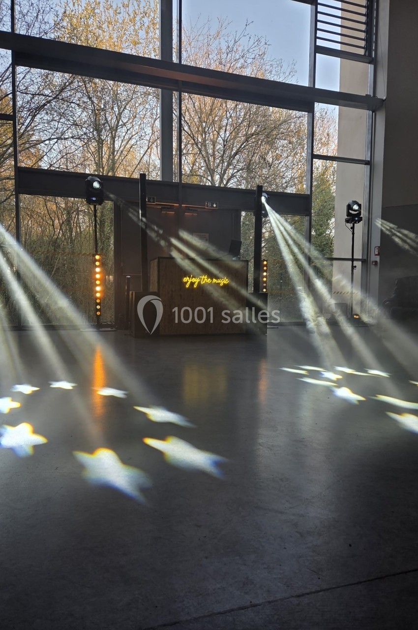 Jeu de lumières projeté au sol dans une salle avec une scène équipée de matériel audio et visuel.