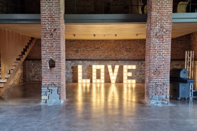Bar en pierre avec comptoir sombre, quatre tabourets noirs et un sol en carreaux gris foncé dans une ambiance rustique.