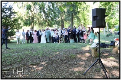 Groupe de personnes posant pour une photo en extérieur, entourées d'arbres, avec un haut-parleur au premier plan.