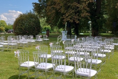 Chaises transparentes alignées en extérieur sur une pelouse, préparées pour une cérémonie en plein air.