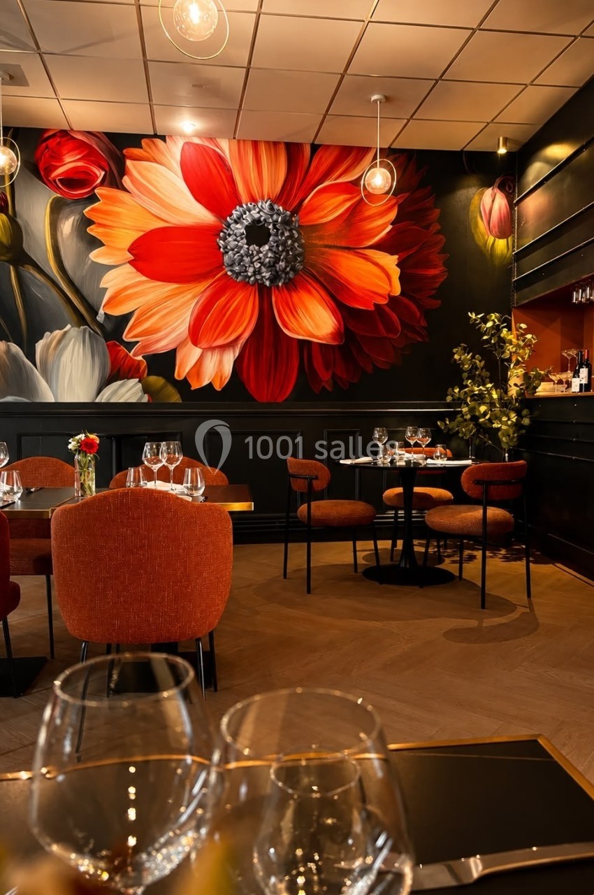 Salle de restaurant élégante avec fresque murale florale colorée, tables dressées et ambiance chaleureuse.