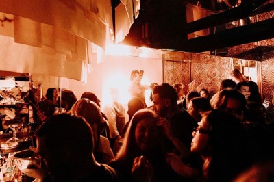 Bar illuminé avec un grand lustre suspendu, vu à travers une vitre floue dans une ambiance tamisée.
