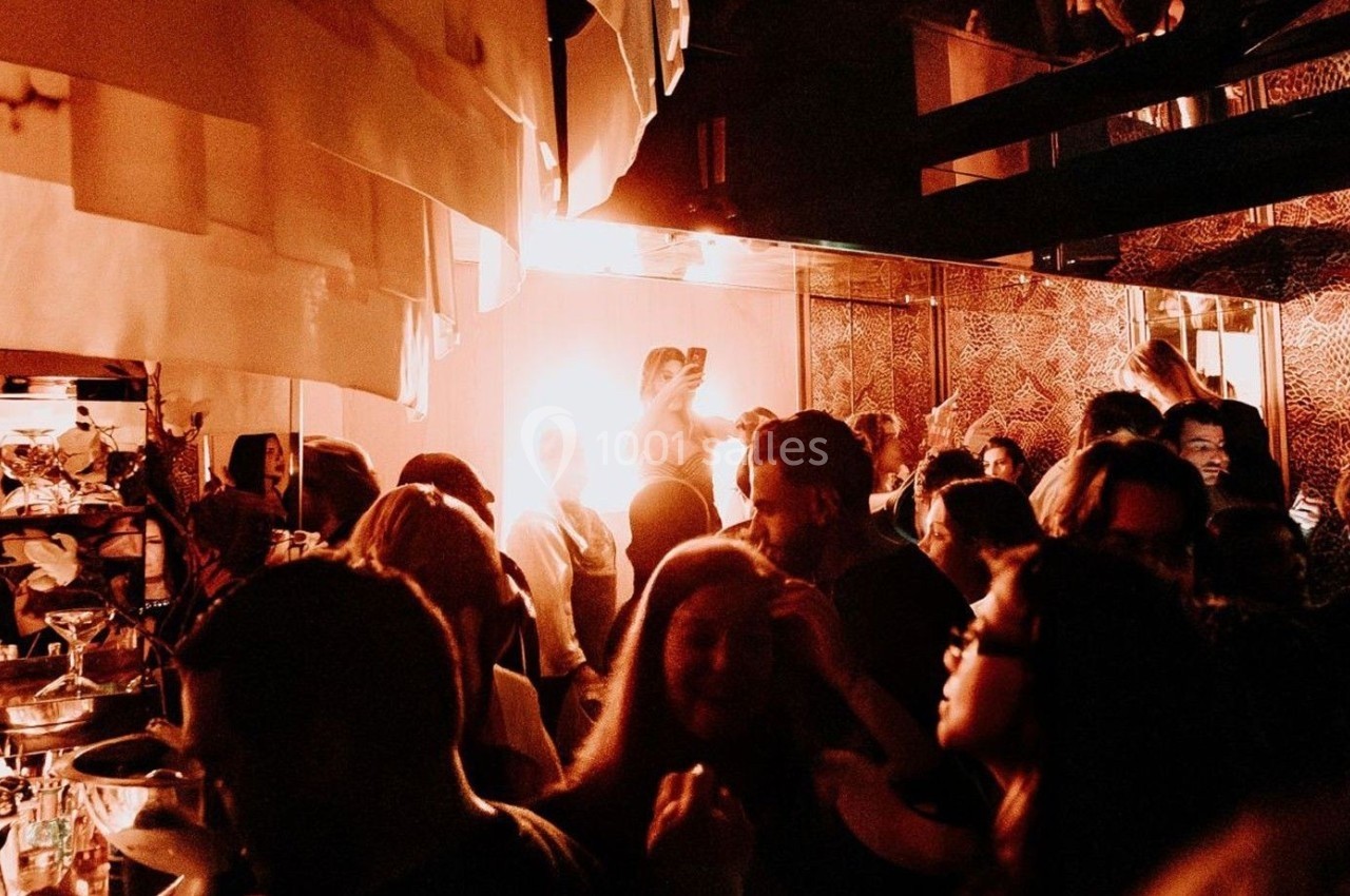 Foule rassemblée dans un espace intérieur faiblement éclairé, ambiance festive avec éclairage chaleureux.