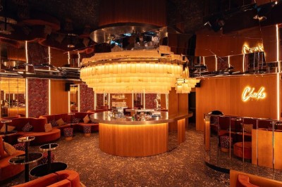 Bar illuminé avec un grand lustre suspendu, vu à travers une vitre floue dans une ambiance tamisée.