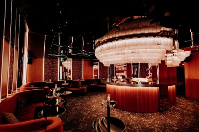 Bar illuminé avec un grand lustre suspendu, vu à travers une vitre floue dans une ambiance tamisée.