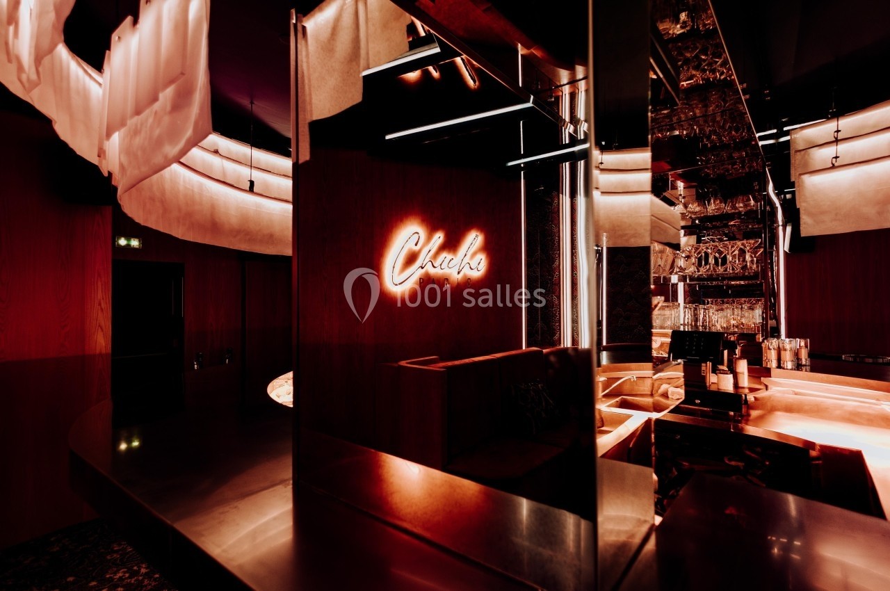 Enseigne lumineuse ’Chale’ dans un intérieur moderne avec éclairage tamisé et surfaces métalliques réfléchissantes.