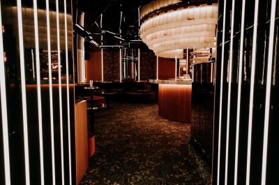 Bar illuminé avec un grand lustre suspendu, vu à travers une vitre floue dans une ambiance tamisée.