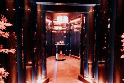 Bar illuminé avec un grand lustre suspendu, vu à travers une vitre floue dans une ambiance tamisée.