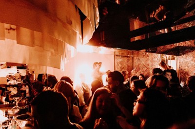 Bar illuminé avec un grand lustre suspendu, vu à travers une vitre floue dans une ambiance tamisée.