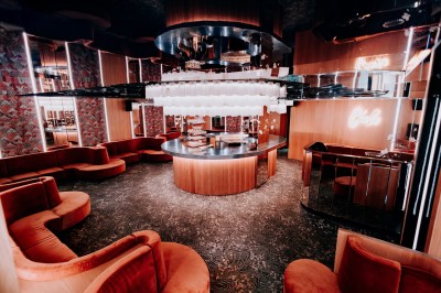 Bar illuminé avec un grand lustre suspendu, vu à travers une vitre floue dans une ambiance tamisée.