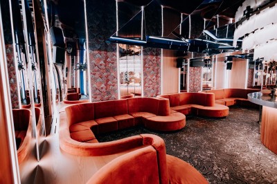 Bar illuminé avec un grand lustre suspendu, vu à travers une vitre floue dans une ambiance tamisée.