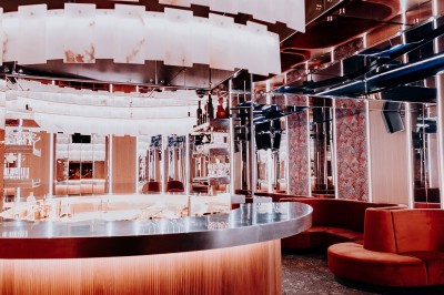 Bar illuminé avec un grand lustre suspendu, vu à travers une vitre floue dans une ambiance tamisée.