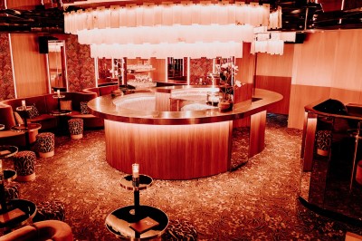 Bar illuminé avec un grand lustre suspendu, vu à travers une vitre floue dans une ambiance tamisée.