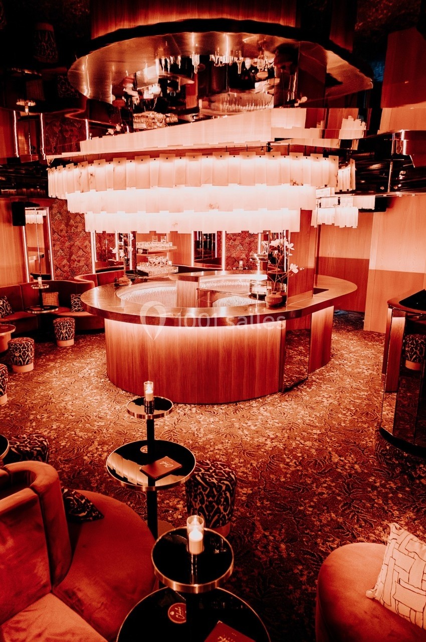 Intérieur d'un bar élégant avec comptoir arrondi, éclairage tamisé et sièges confortables dans une ambiance chaleureuse.