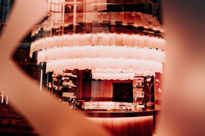 Bar illuminé avec un grand lustre suspendu, vu à travers une vitre floue dans une ambiance tamisée.