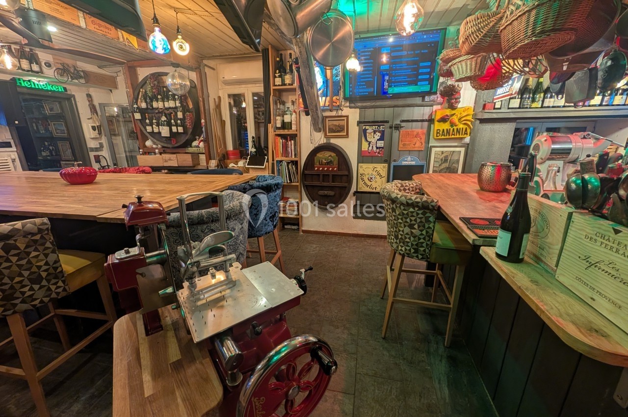 Intérieur d'un bar ou restaurant avec des tables en bois, des chaises colorées et une décoration éclectique.