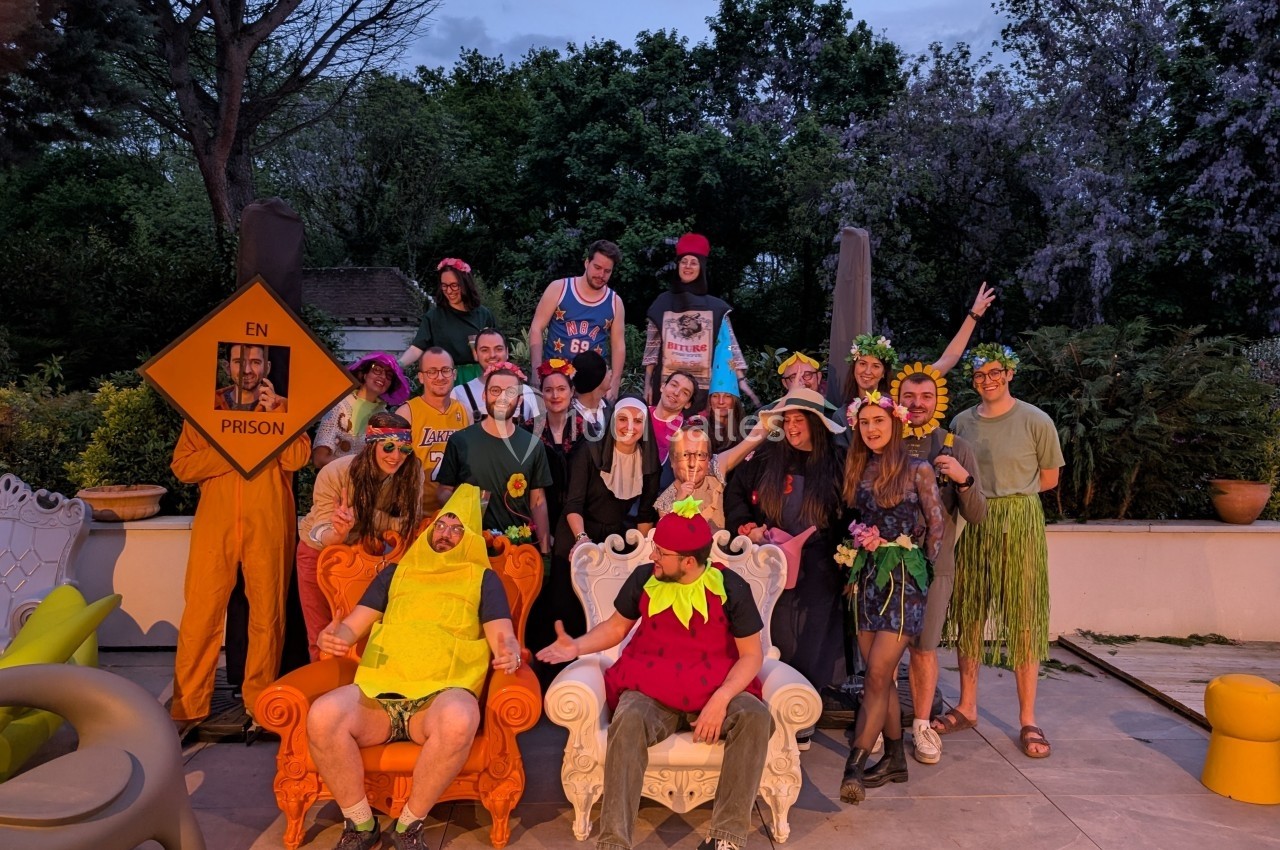 Un groupe de personnes déguisées en costumes variés posant dans un jardin en soirée.