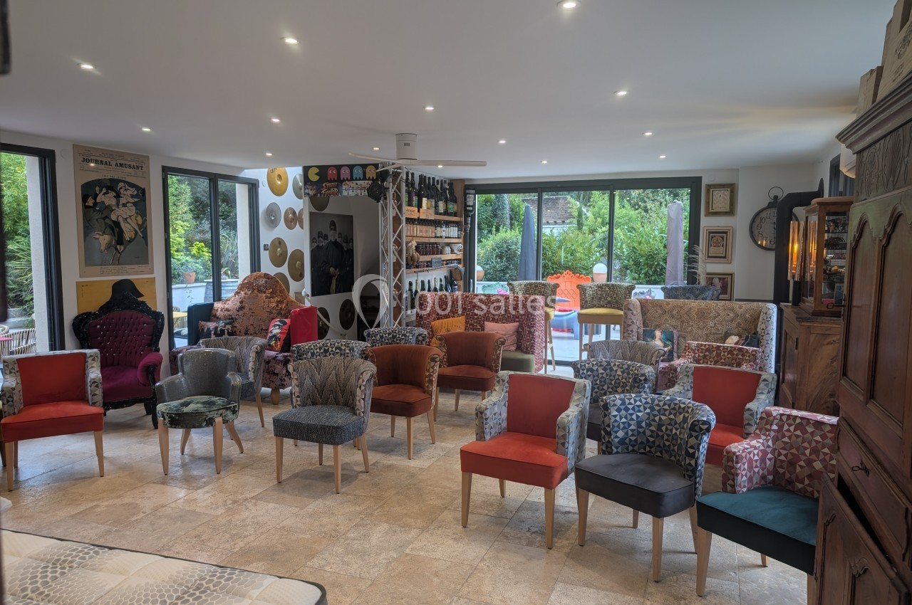 Salle lumineuse avec des chaises colorées disposées face à une scène, entourée de grandes baies vitrées donnant sur un…
