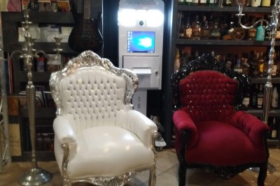 Batterie blanche installée sur une scène éclairée, entourée d'amplificateurs et de structures métalliques.