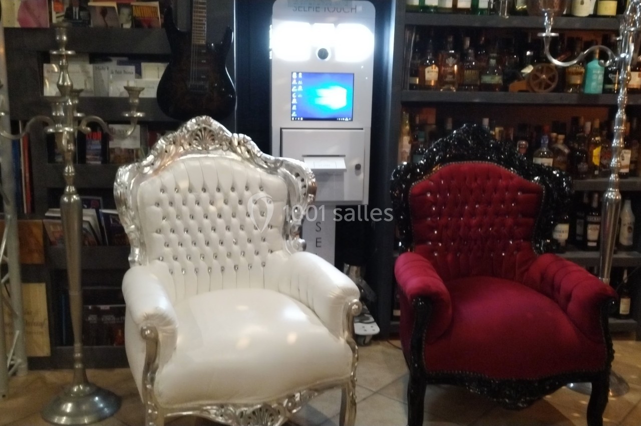 Deux fauteuils baroques, l'un blanc et l'autre rouge, placés devant un distributeur automatique dans un décor de bar.