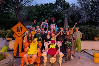 Batterie blanche installée sur une scène éclairée, entourée d'amplificateurs et de structures métalliques.