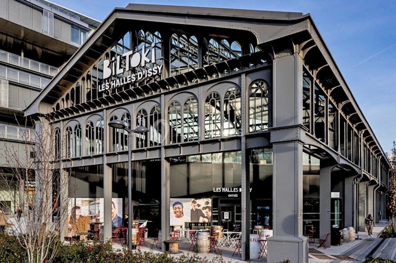 Façade d'un bâtiment industriel rénové abritant des commerces et restaurants, entouré d'espaces urbains modernes.