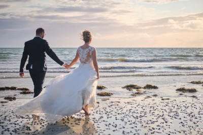 Un couple danse sous des lumières colorées et une ambiance de fumée lors d'une réception festive.