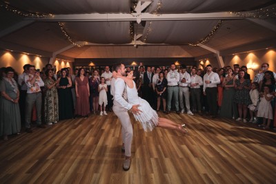 Un couple danse sous des lumières colorées et une ambiance de fumée lors d'une réception festive.