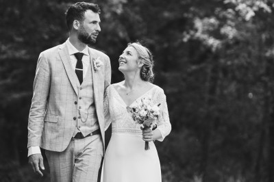 Un couple danse sous des lumières colorées et une ambiance de fumée lors d'une réception festive.