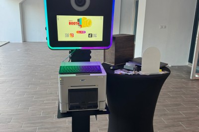Borne photo interactive avec écran, éclairage circulaire et imprimante intégrée, installée dans une salle lumineuse.