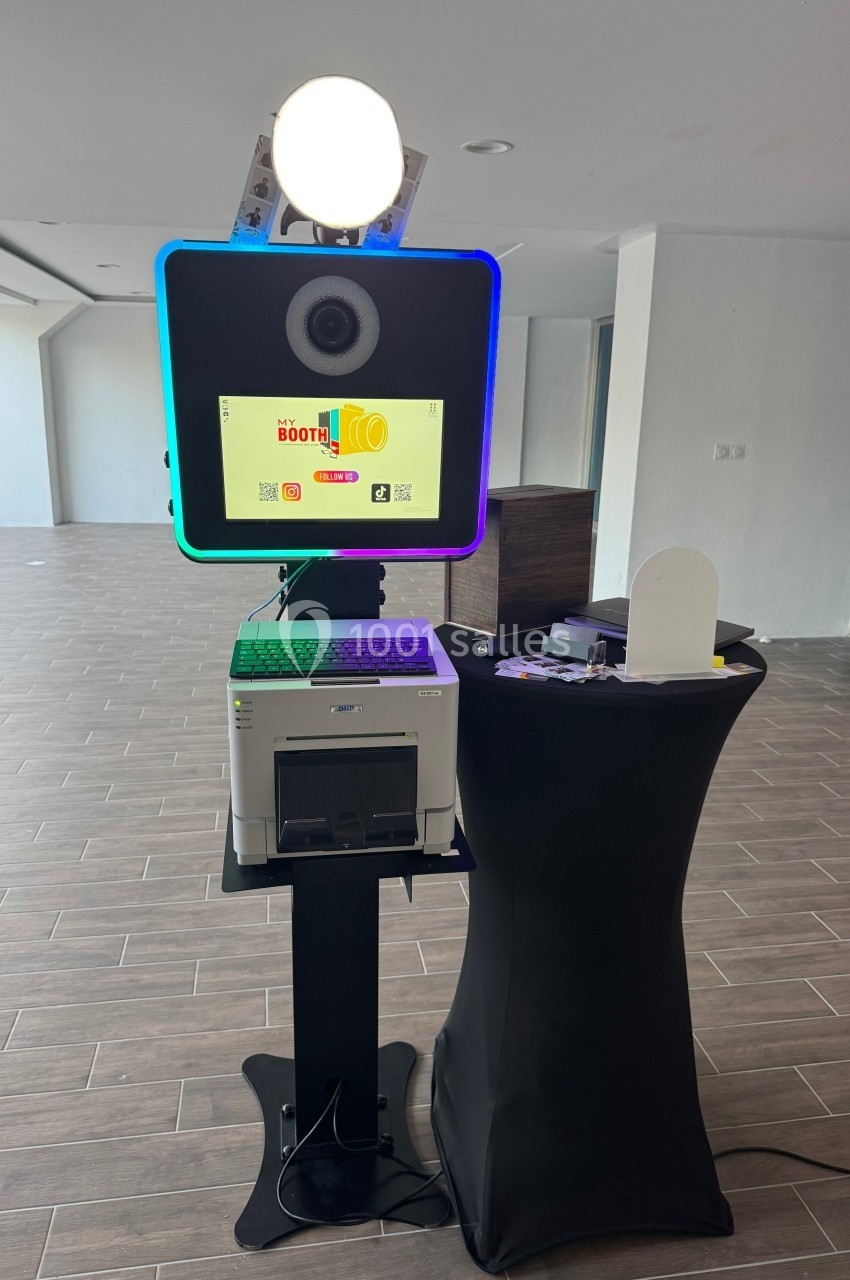 Borne photo interactive avec écran, imprimante et accessoires, installée dans un espace intérieur moderne.