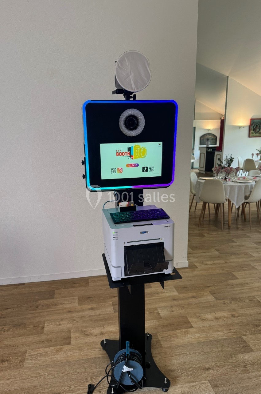 Borne photo interactive avec écran, éclairage circulaire et imprimante intégrée, installée dans une salle lumineuse.