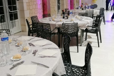 Salle de réception décorée pour un anniversaire, avec tables alignées, guirlandes et lanternes suspendues au plafond en bois.