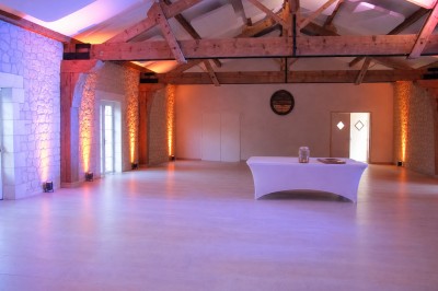 Salle de réception décorée pour un anniversaire, avec tables alignées, guirlandes et lanternes suspendues au plafond en bois.