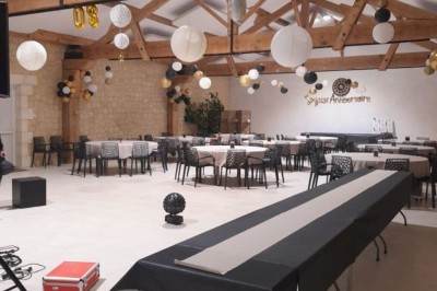 Miniature Location salle Les Mathes (Charente-Maritime) - Logis de la Palmeraie #16 Salle de réception décorée pour un anniversaire, avec tables alignées, guirlandes et lanternes suspendues au plafond en bois.