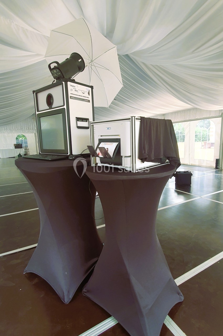 Borne photo avec éclairage et accessoires, installée sous une tente sur des tables recouvertes de housses noires.